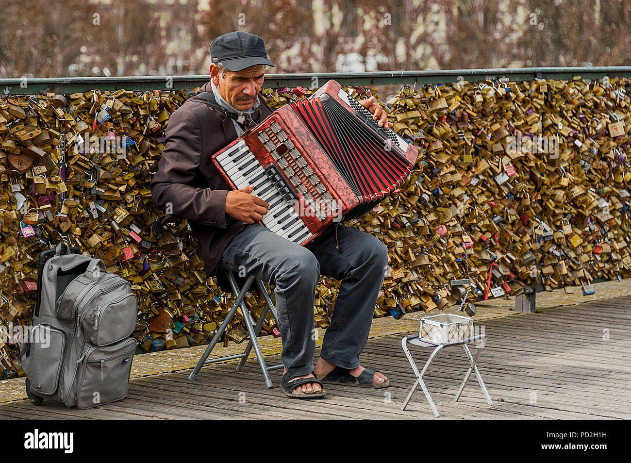 Paris, France - 21 juillet 2014 : Vieil homme sur un tabouret à l'accordéon pour obtenir des conseils sur le Pont des Arts Bridge - un pont sur la Seine à Paris. Banque D'Images