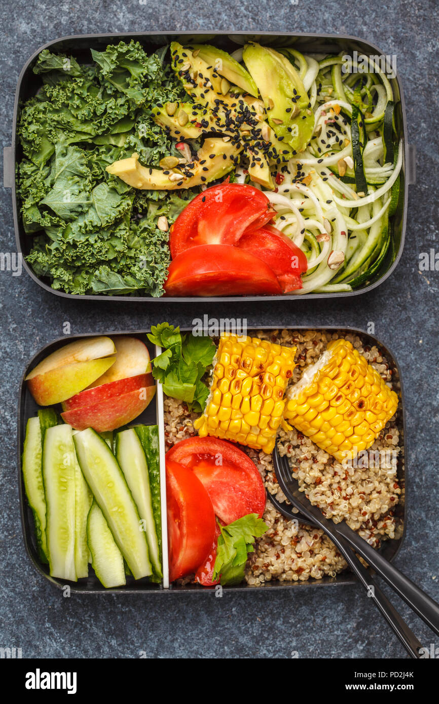 Préparation des repas sains avec des conteneurs le quinoa, l'avocat, le maïs, les courgettes nouilles et le chou frisé. La nourriture à emporter. Fond sombre, vue du dessus. Banque D'Images