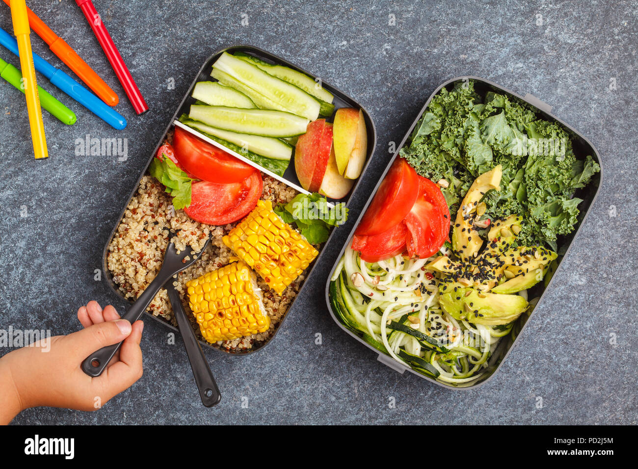 Préparation des repas sains avec des conteneurs le quinoa, l'avocat, le maïs, les courgettes nouilles et le chou frisé. La nourriture à emporter à l'école. Fond sombre, vue du dessus. Banque D'Images