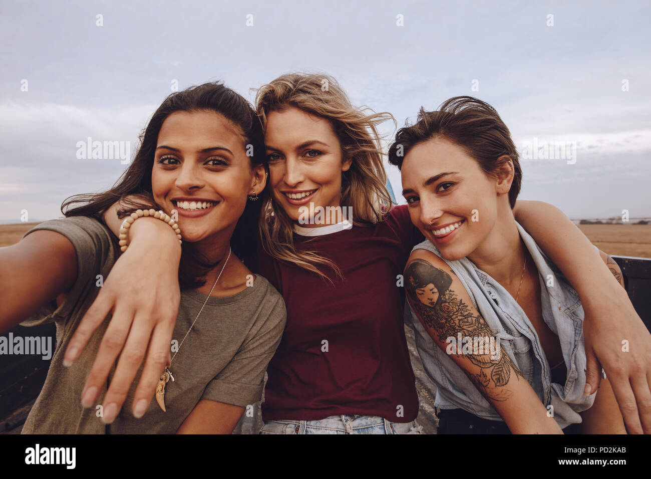 Belles femmes de prendre en voyage par un selfies pickup. Trois jeunes amis féminins posant pour une ouverture dans un selfies retour chariot en campagne. Banque D'Images