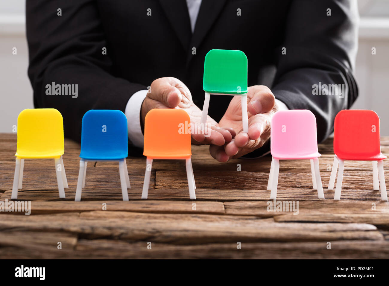 La main d'affaires prendre fauteuil vert entre autres sur un bureau en bois Banque D'Images