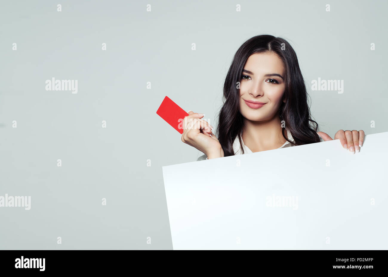 Smiling business woman showing red carte vide et holding white blank banner backround. Des affaires, de la publicité et du placement de produit marketing concept Banque D'Images