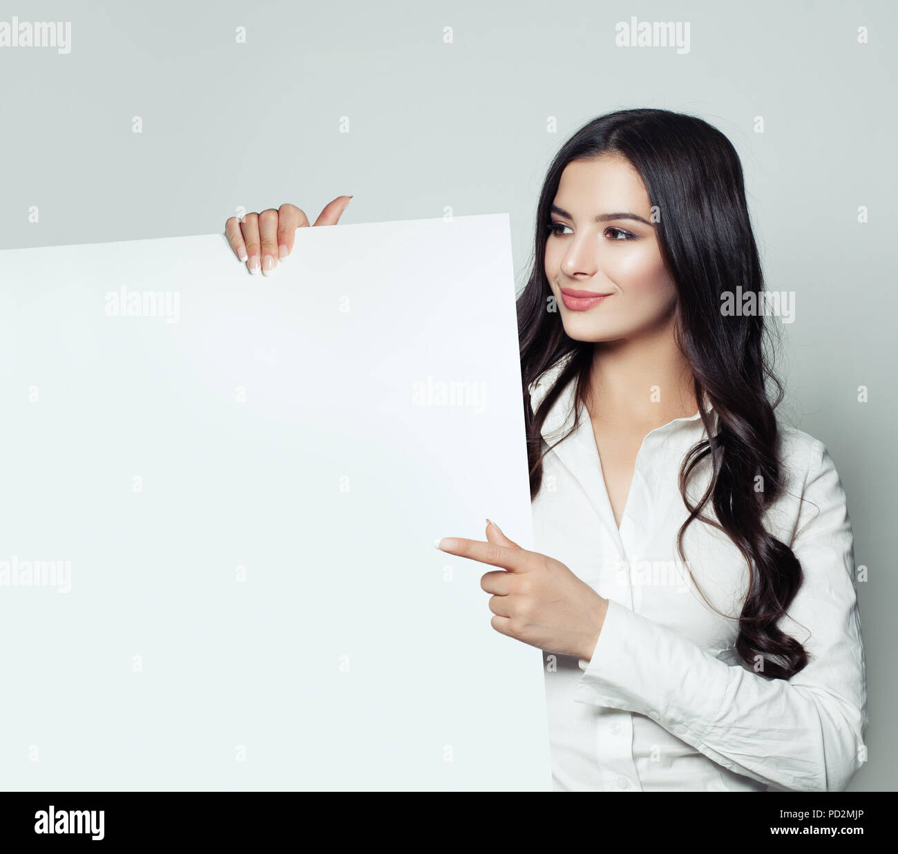 Happy business woman smiling brunette, montrant le papier blanc vide arrière plan de la bannière et de pointage. Smart student woman portrait, l'entreprise et de l'éducation Banque D'Images