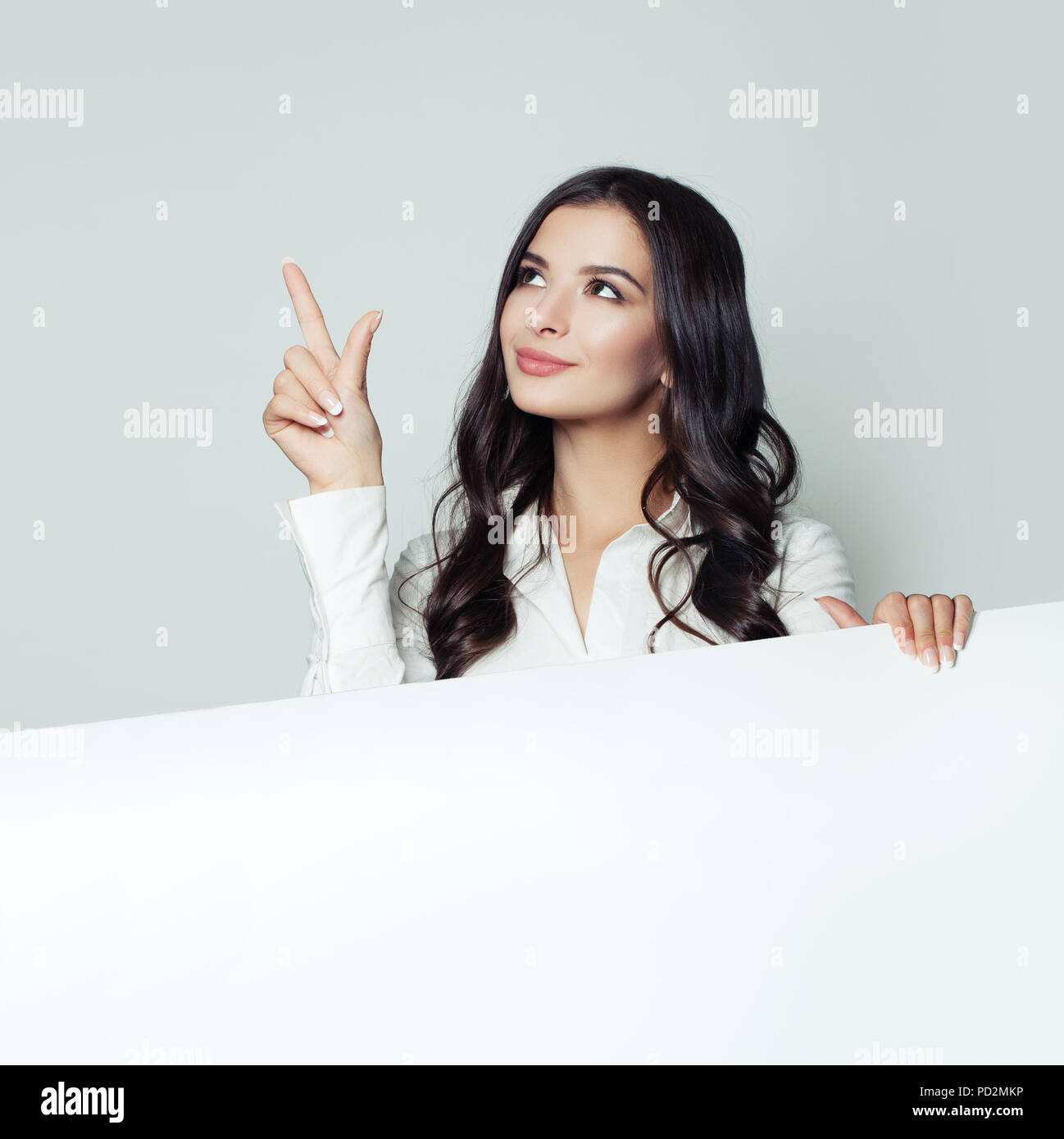 Élève qui fait preuve d'arrière-plan de papier vide blanc et pointant vers le haut son doigt. Portrait d'étudiant, l'entreprise et de l'éducation concept Banque D'Images