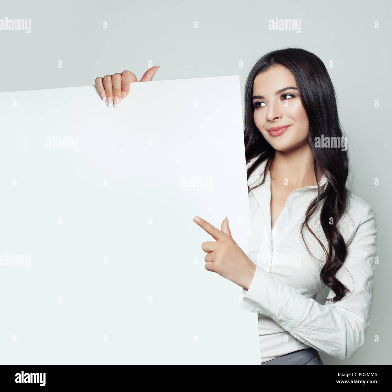 Smiling business woman pointant vers le haut et montrant pancarte avec copie espace vide pour slogan, advertisiment ou message texte sur fond blanc. Su Banque D'Images