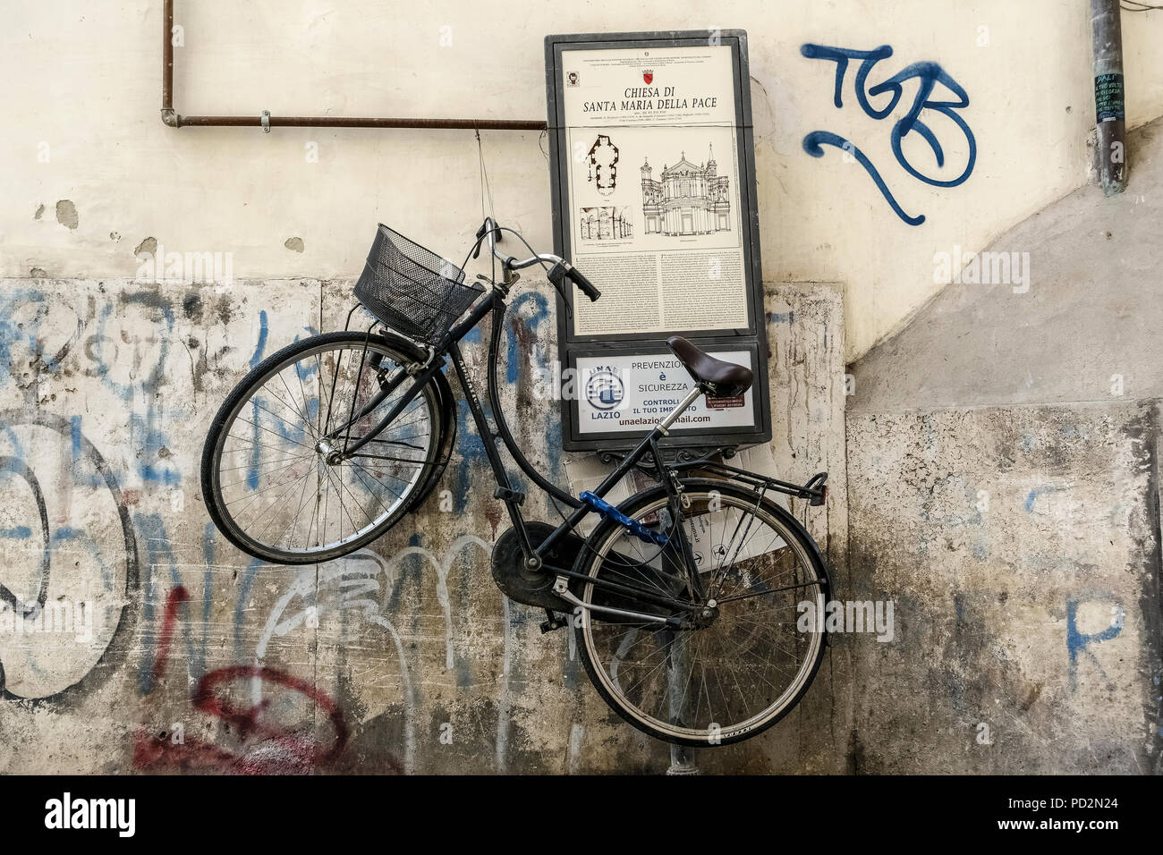 Vélo noir avec panier, garé suspendu sur un panneau touristique. Centre ville de Rome, Italie, Europe, Union européenne, UE. Banque D'Images