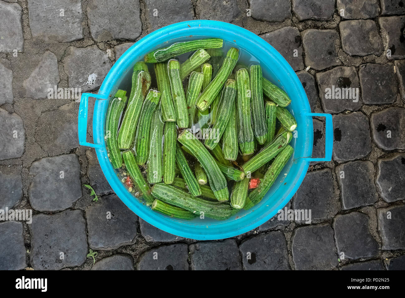 Trempés de courgettes dans un bol en plastique sur la chaussée d'un marché à Rome, Italie Europe, UE. Courgettes légumes, végétarien, nourriture de régime végétalien. Banque D'Images