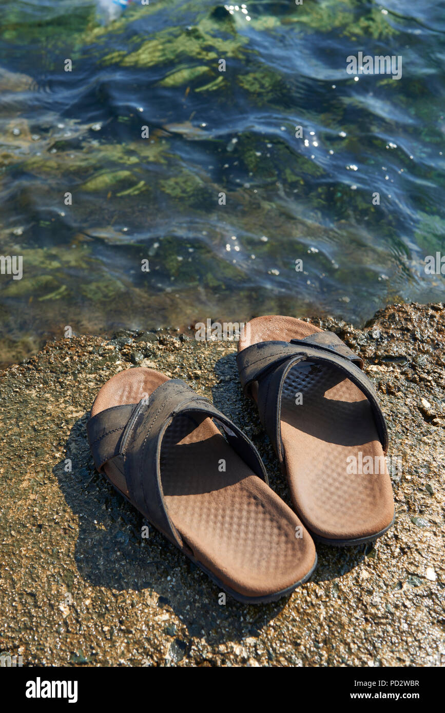 Une paire de sandales en cuir pour hommes à bord de l'eau par la mer Banque D'Images
