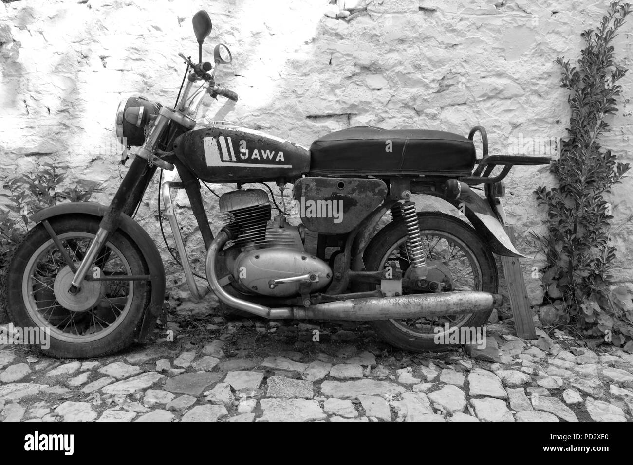 Noir et blanc (monochrome) shot de tchèque Jawa Classic vintage moto en stationnement sur rue pavée, contre un mur blanc en Albanie Banque D'Images