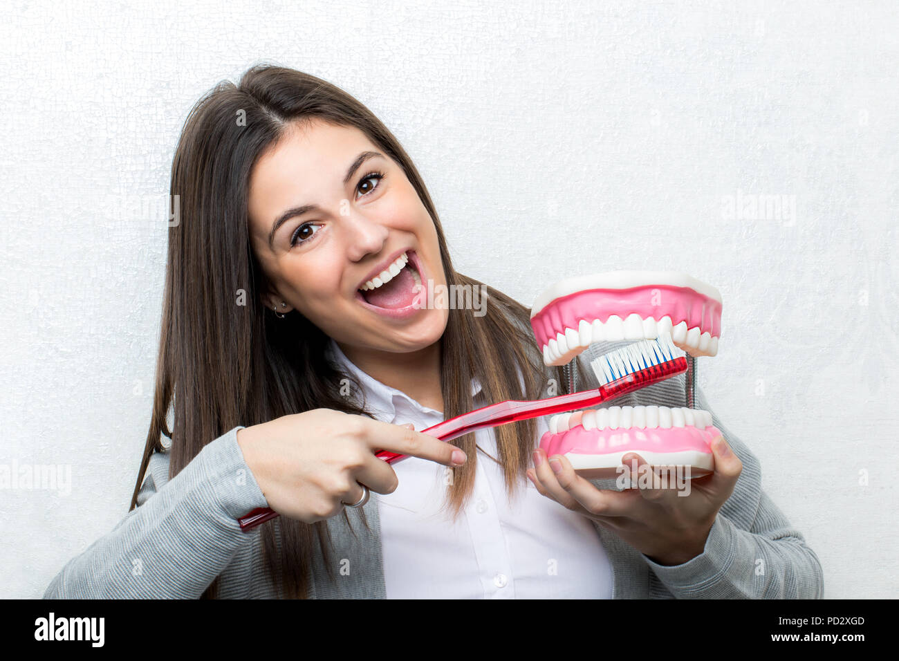 Relations sérieuses in Close up portrait of young girl montrant des dents humaines prothèse.femme nettoyer les dents sur prothèse avec une brosse à dents contre lig Banque D'Images