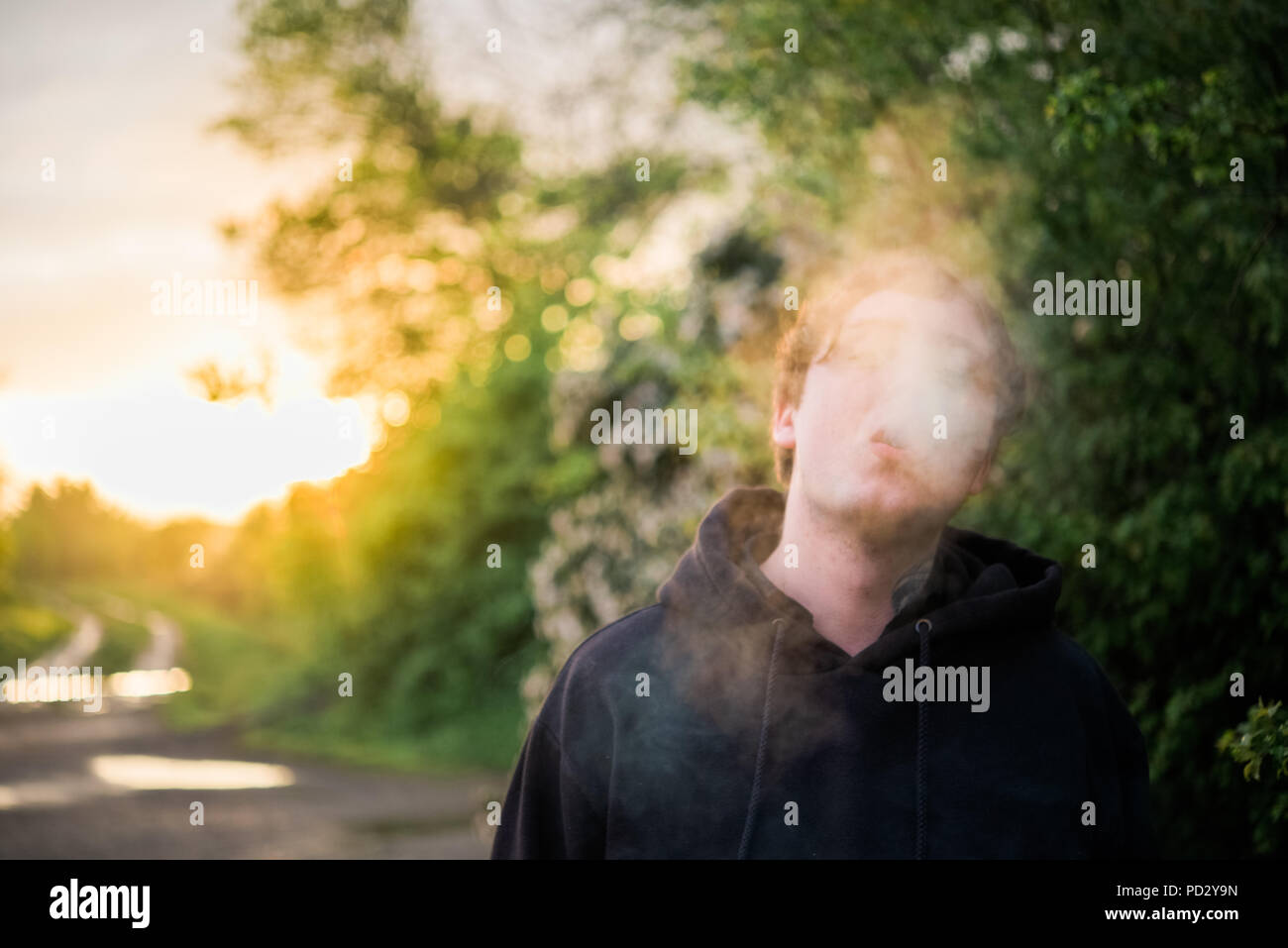 L'homme avec la fumée de cigarette face obscurcissant Banque D'Images