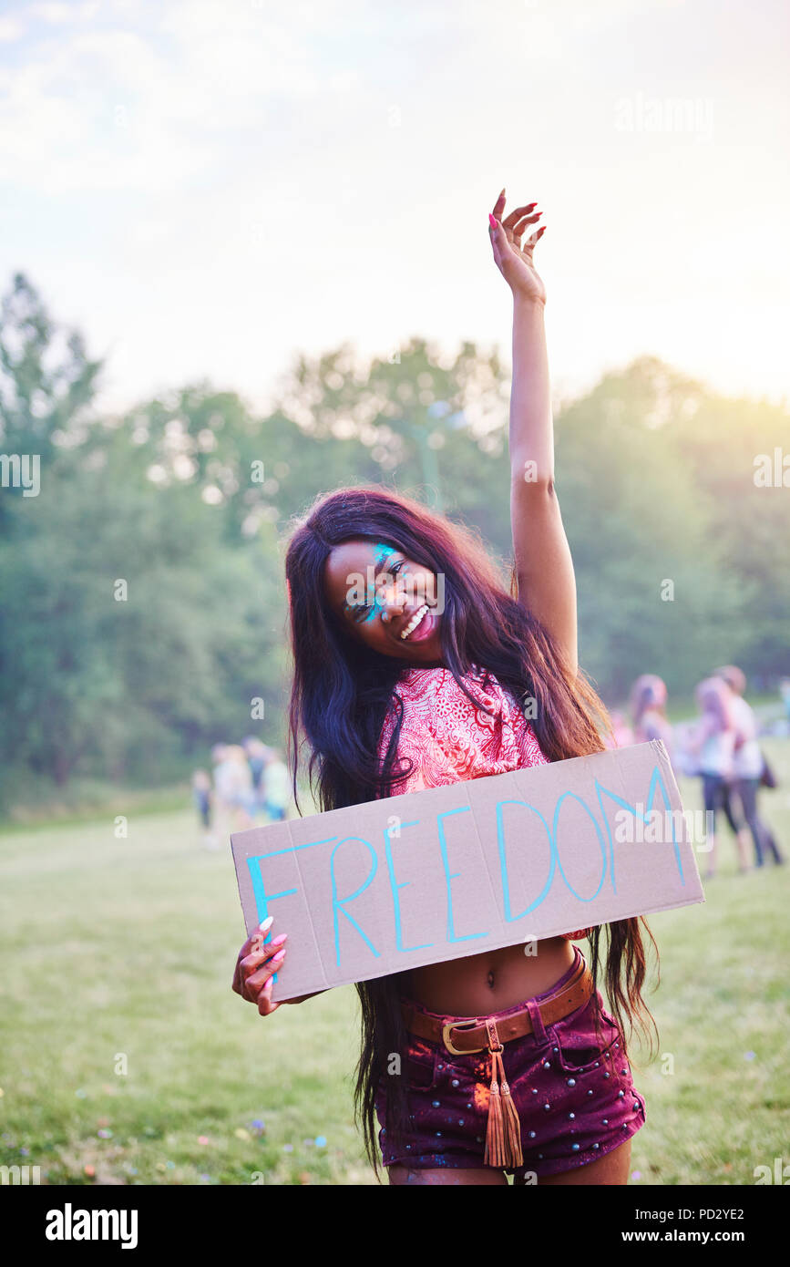 Jeune femme danser tout en maintenant la liberté de signer au Festival Holi, portrait Banque D'Images