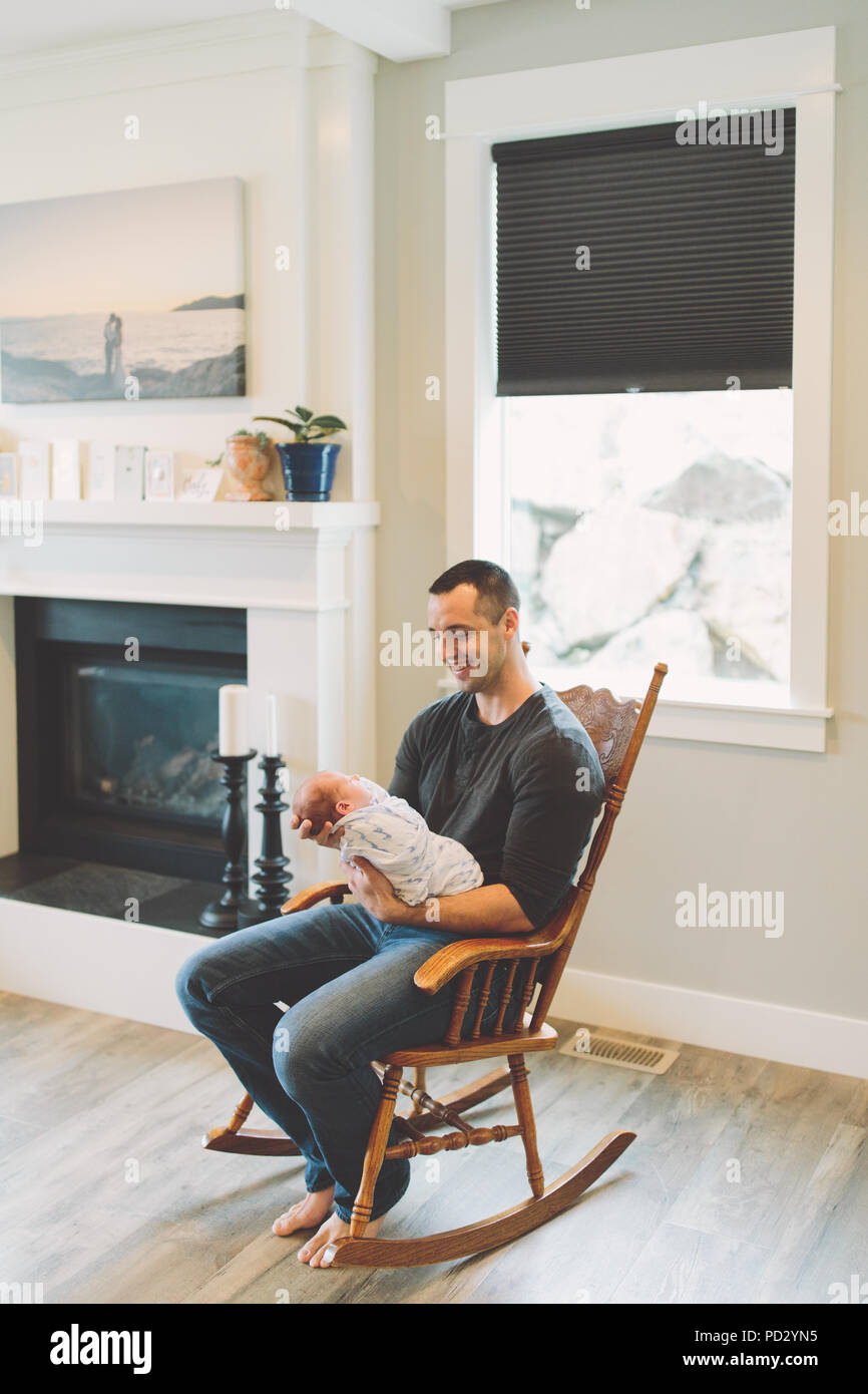 Père assis dans un rocking-chair holding newborn baby boy Banque D'Images