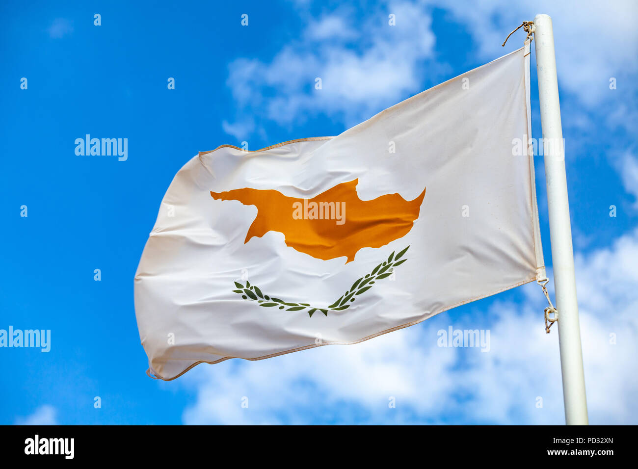 Brandissant le drapeau national de Chypre sur un mât plus nuageux ciel bleu Banque D'Images