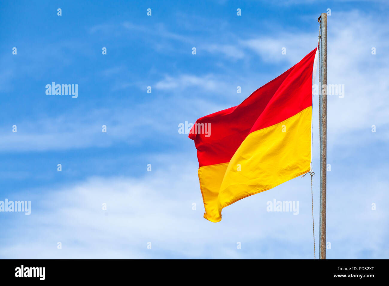 Un indicateur d'alerte rouge et jaune sur une plage sur fond de ciel bleu Banque D'Images Un indicateur d'alerte rouge et jaune sur une plage sur fond de ciel bleu Banque D'Images