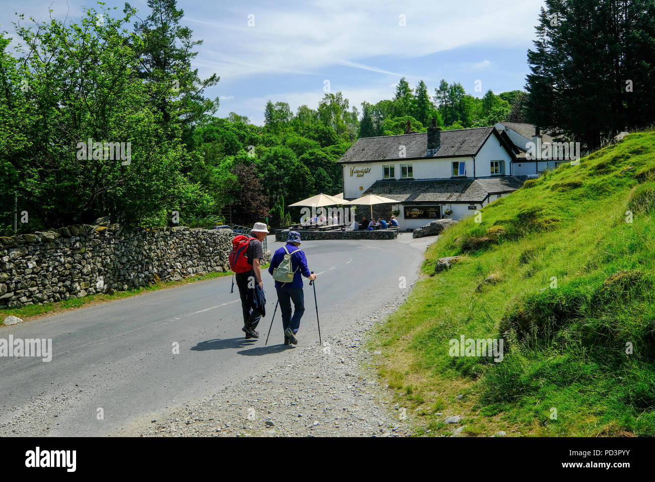 Deux marcheurs en direction d'un pub traditionnel dans le Lake District Banque D'Images