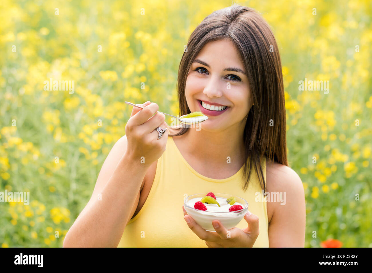 Close up portrait of attractive girl eating yoghurt sain avec des fruits à l'extérieur. Banque D'Images