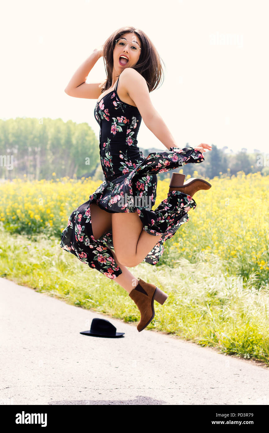 Action pleine longueur portrait de jeune fille en robe à fleurs à l'extérieur de saut. Banque D'Images