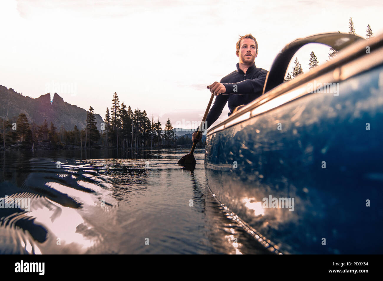 Jeune homme canoë sur Echo Lake, High Sierras, California, USA Banque D'Images