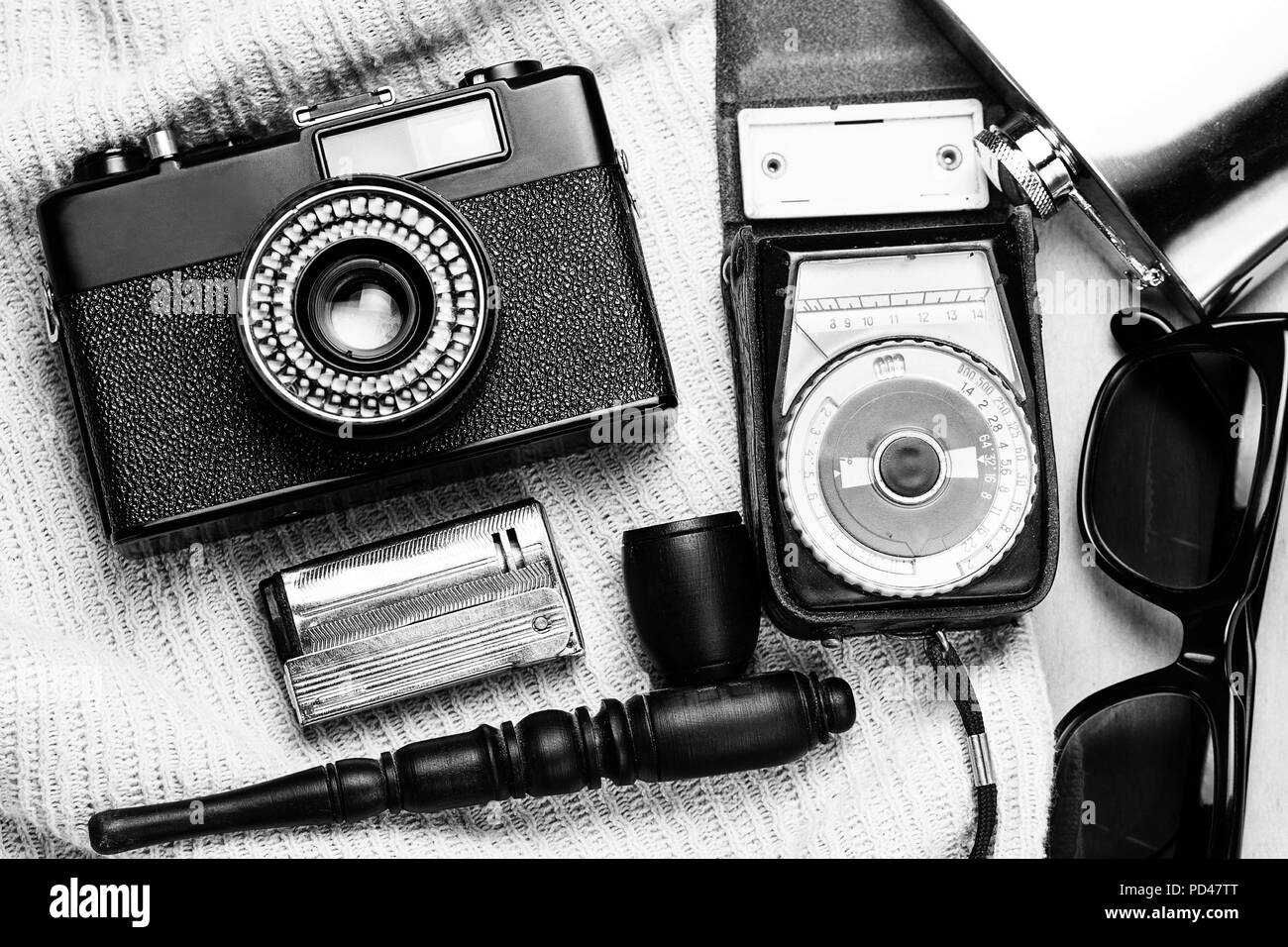 Accessoires de la personne créative. 35-mm, mesure d'exposition en cas de cuir, d'acier, des lunettes de soleil et fiole fumeurs mis sur fond de bois. Banque D'Images
