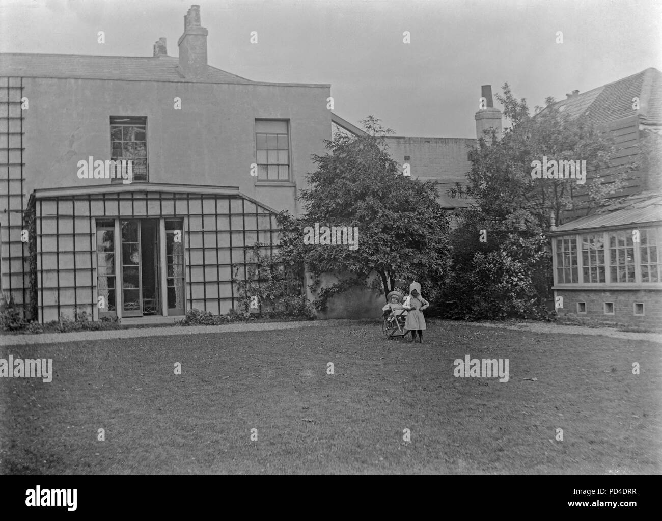 Alate photographie victorienne montrant deux jeunes filles dans le jardin il d'une grande maison en Angleterre. Photo montre de bons exemples de la mode enfantine de l'époque. Banque D'Images