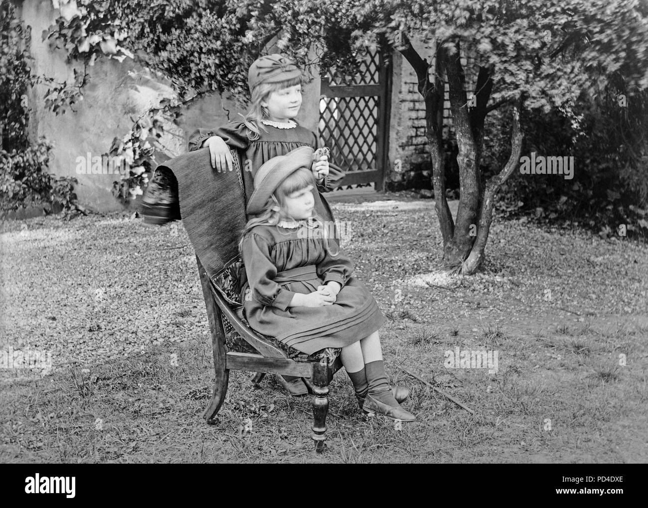 Fin photographie victorienne de deux soeurs, l'un assis, les autres debout, dans un jardin en Angleterre. Photo montre les détails de la mode des vêtements pour enfants de l'époque. Banque D'Images