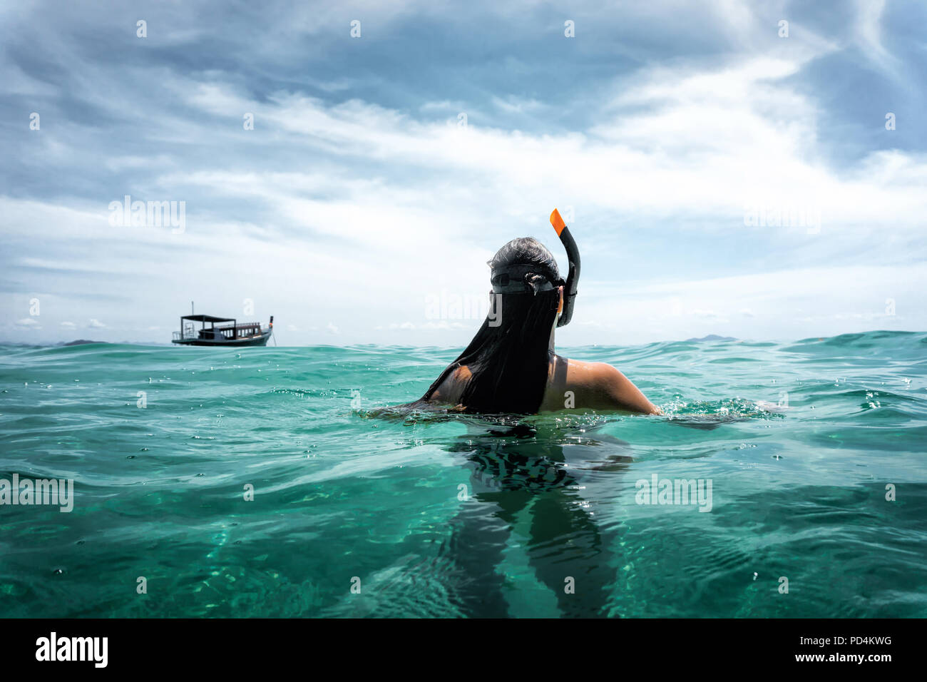 Jeune femme de derrière nage dans la mer ouverte alors que la plongée libre avec ciel bleu et nuages au cours de voyage d'été Banque D'Images