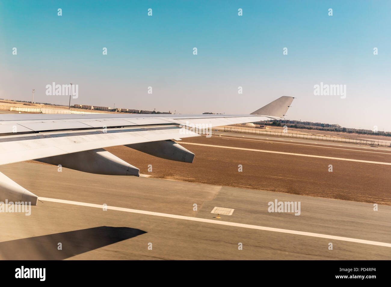 Vue aérienne de la fenêtre de l'avion tout en décollant de la piste de l'aéroport avec désert et ciel bleu Banque D'Images