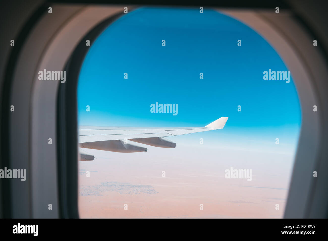 Belle vue de la fenêtre de l'avion dans le ciel bleu et le désert avec des ailes d'avion Banque D'Images