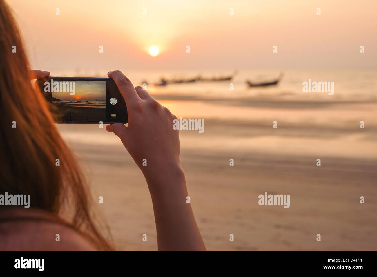 Jeune femme touriste, c'est photographier un coucher du soleil doré avec le smartphone lors de voyages dans le monde Banque D'Images