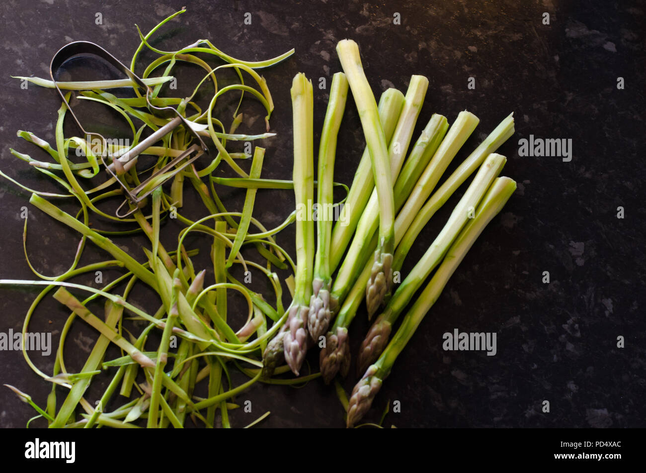 Peler les asperges vertes sur un fond sombre. Banque D'Images Peler les asperges vertes sur un fond sombre. Banque D'Images