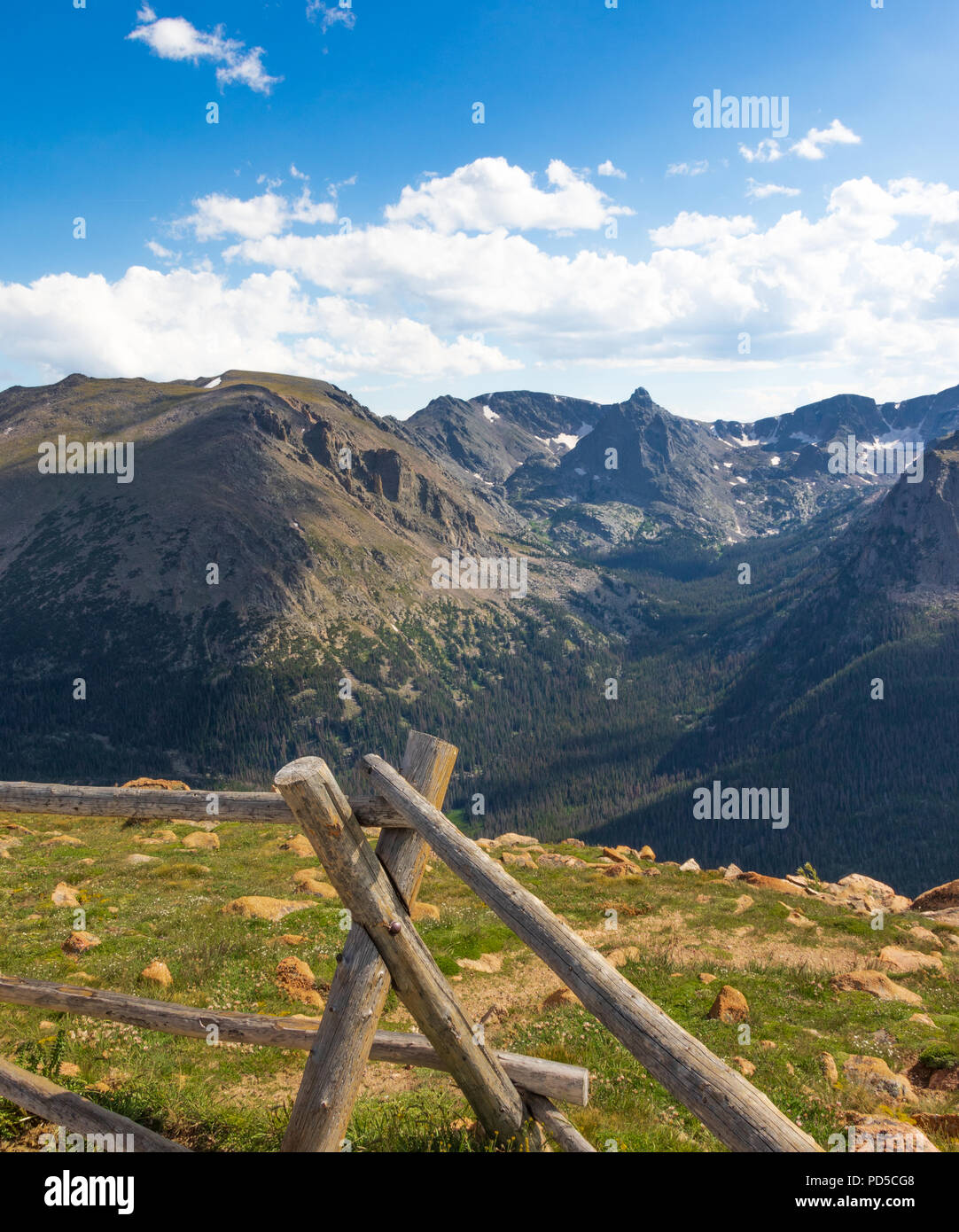 Ensoleillé et lumineux, le Colorado Rocheuses, avec clôture et rock case en face, dramatique, au-delà de montagnes bleu-gris, avec ciel bleu et nuages Banque D'Images