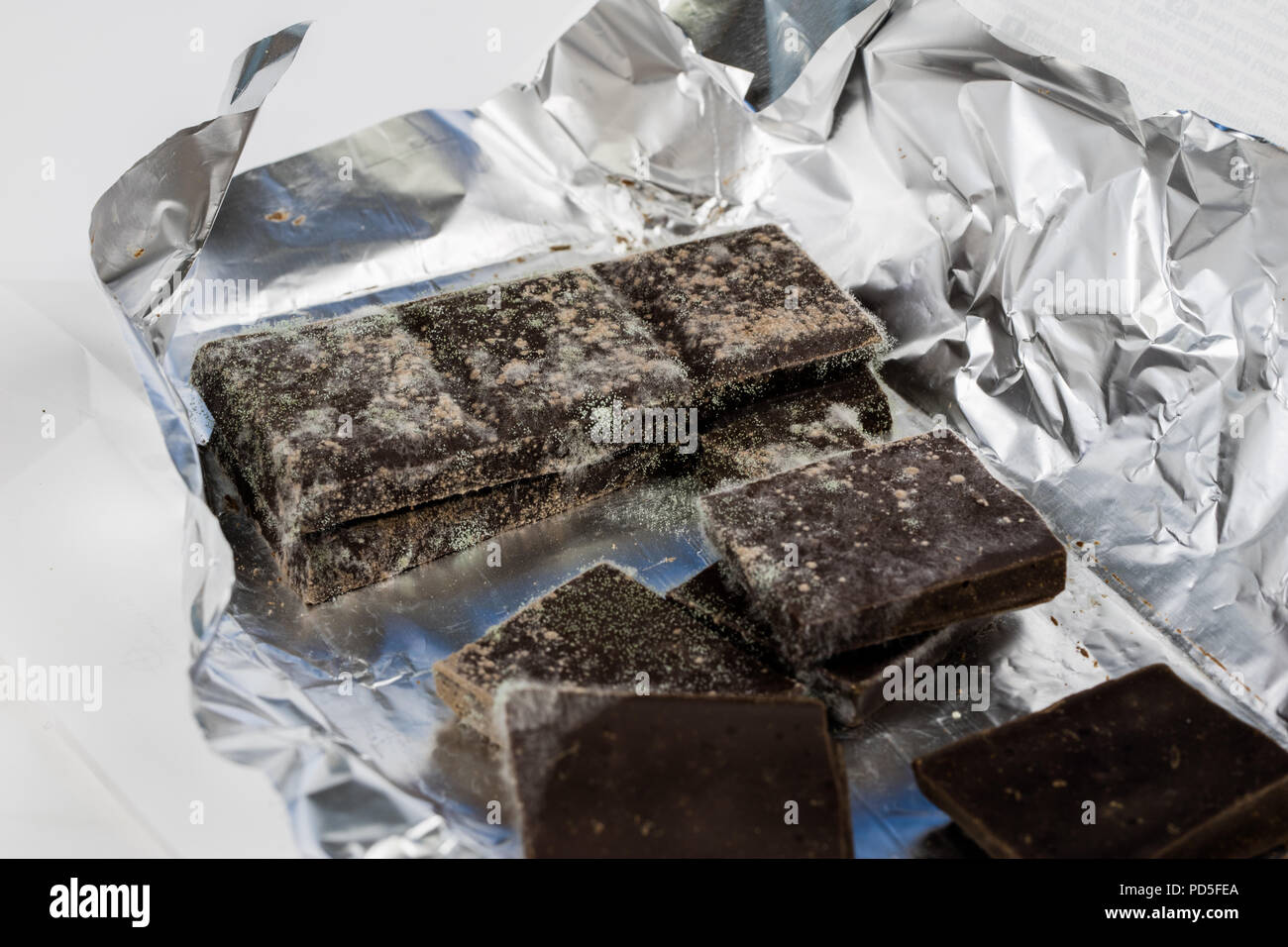 Chocolat moisis dans l'emballage d'origine. Des produits alimentaires utilisés pour les desserts. Arrière-plan blanc. Banque D'Images