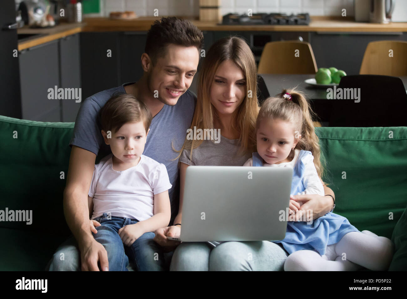 Jeune famille avec enfants en utilisant laptop sitting on sofa Banque D'Images