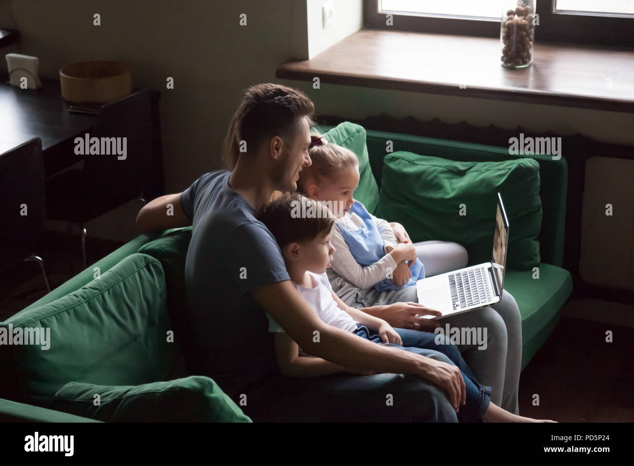 Famille avec enfants regardant la vidéo sur ordinateur portable ensemble sur canapé Banque D'Images