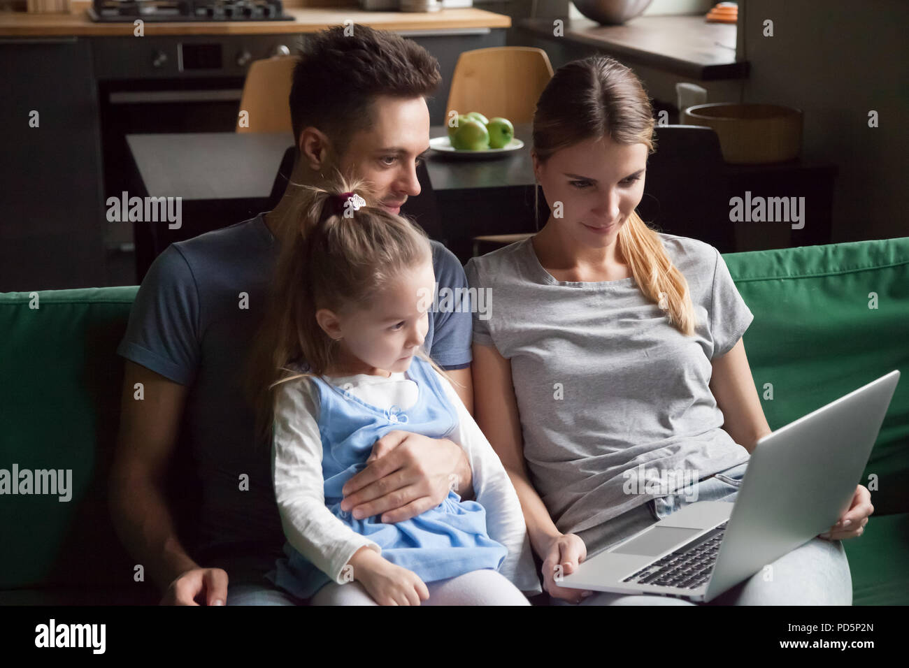 Famille avec fille regardant la vidéo sur ordinateur portable ensemble sur canapé Banque D'Images