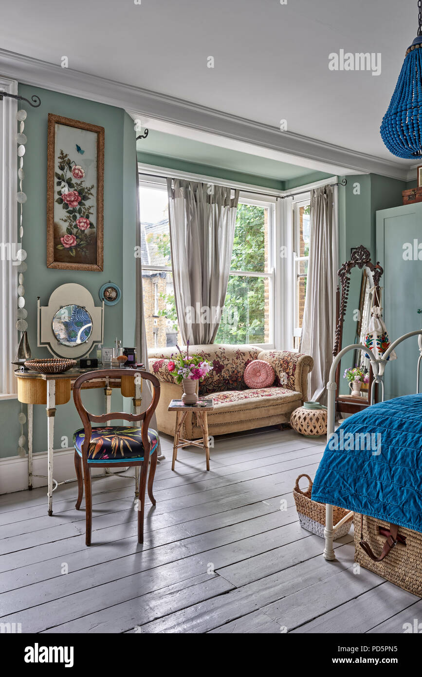 Planchers en bois peint en blanc Farrow & Ball peinture dans la chambre peinte en peu de Greene's placard vert. Le canapé est fleuri des années 20 et Banque D'Images