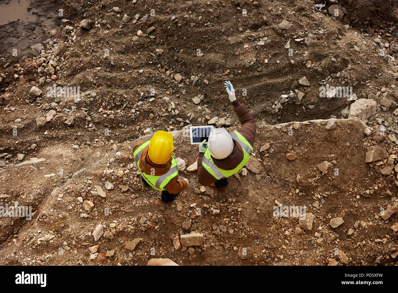 Au-dessus de la photo de deux ouvriers de l'industrie portant des gilets réfléchissants sur le chantier permanent de l'exploitation minière à l'extérieur à l'aide de tablette numérique, copy space Banque D'Images