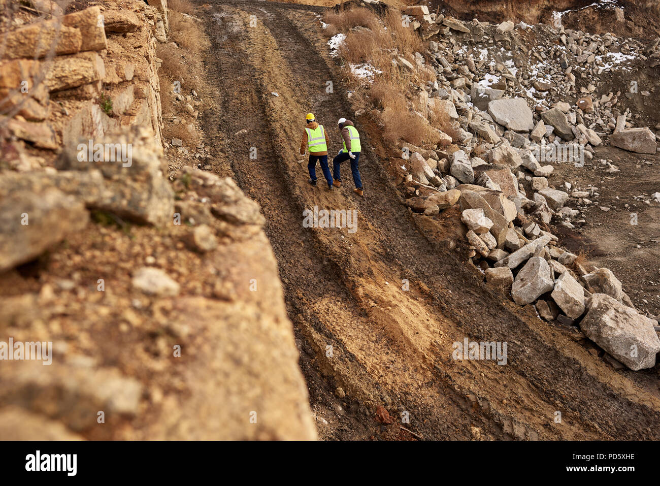 Prise de vue au grand angle de deux ouvriers de l'industrie portant des vestes réfléchissantes marche dans la saleté sur chantier minier, copy space Banque D'Images