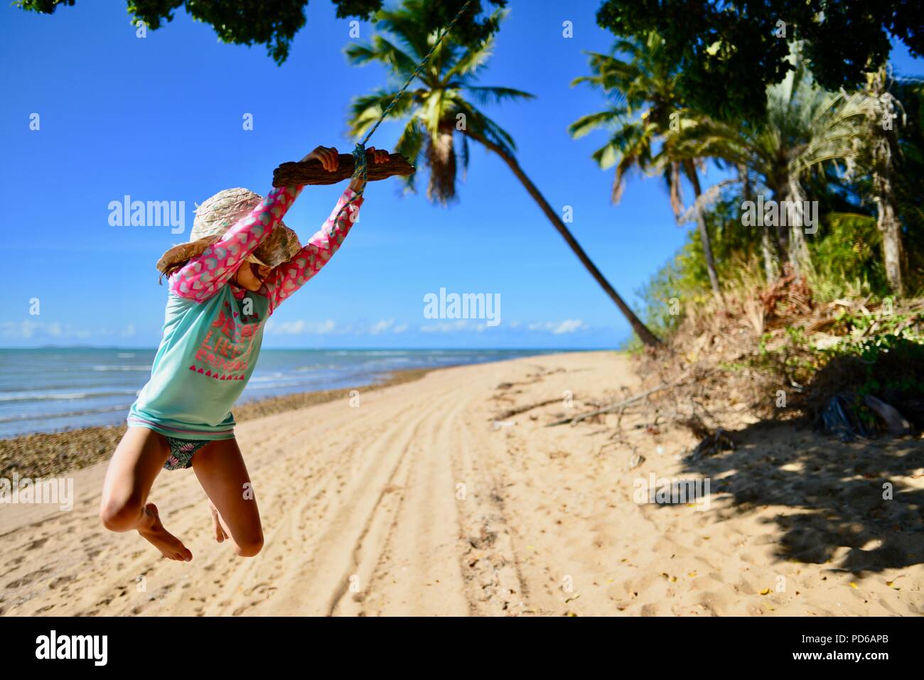 Une Jeune Fille Se Balançant De Corde Sur Une Plage