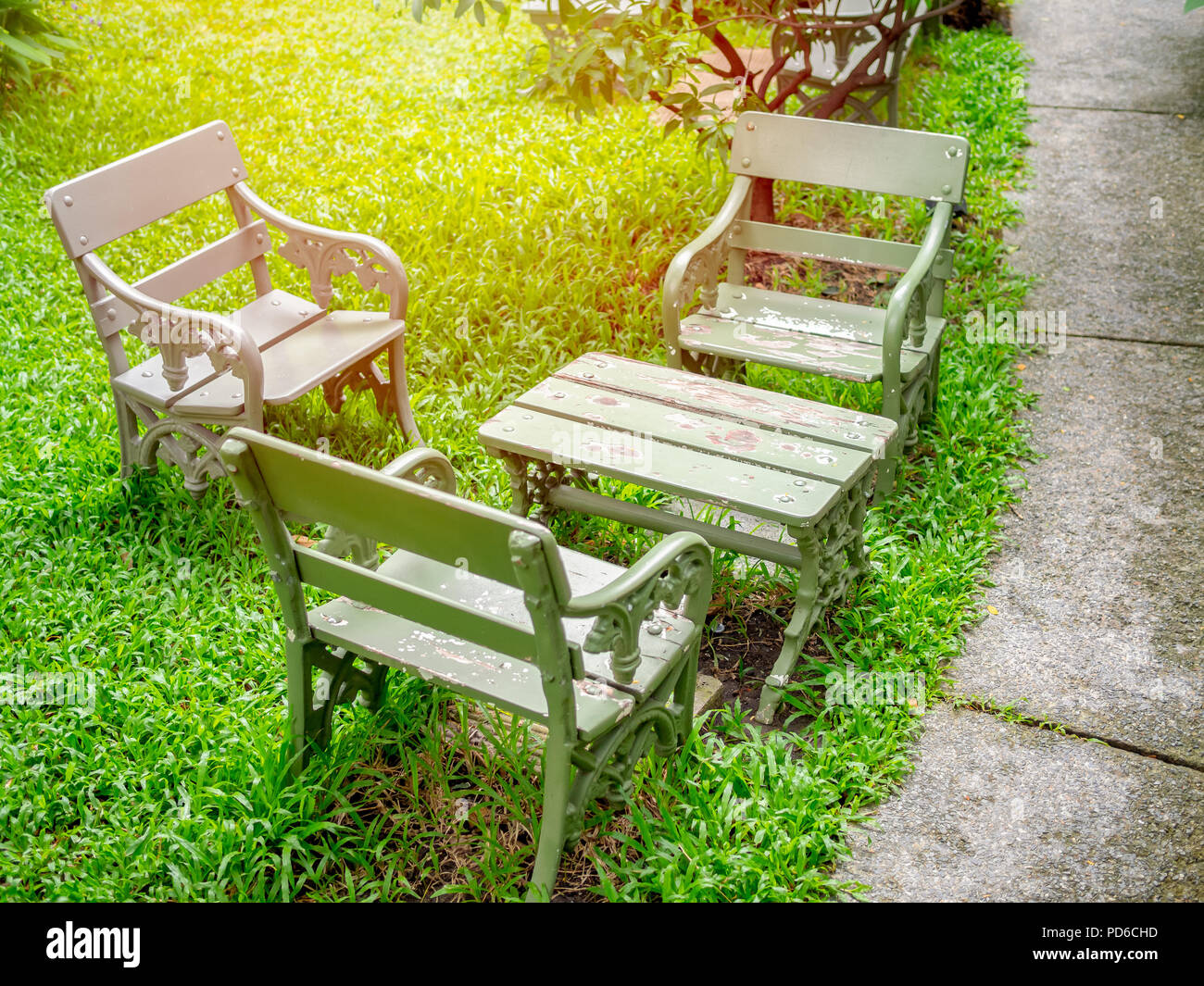 Gris Vintage chaises et table en bois sur l'herbe verte dans le jardin avec une allée piétonnière en ciment. Banque D'Images