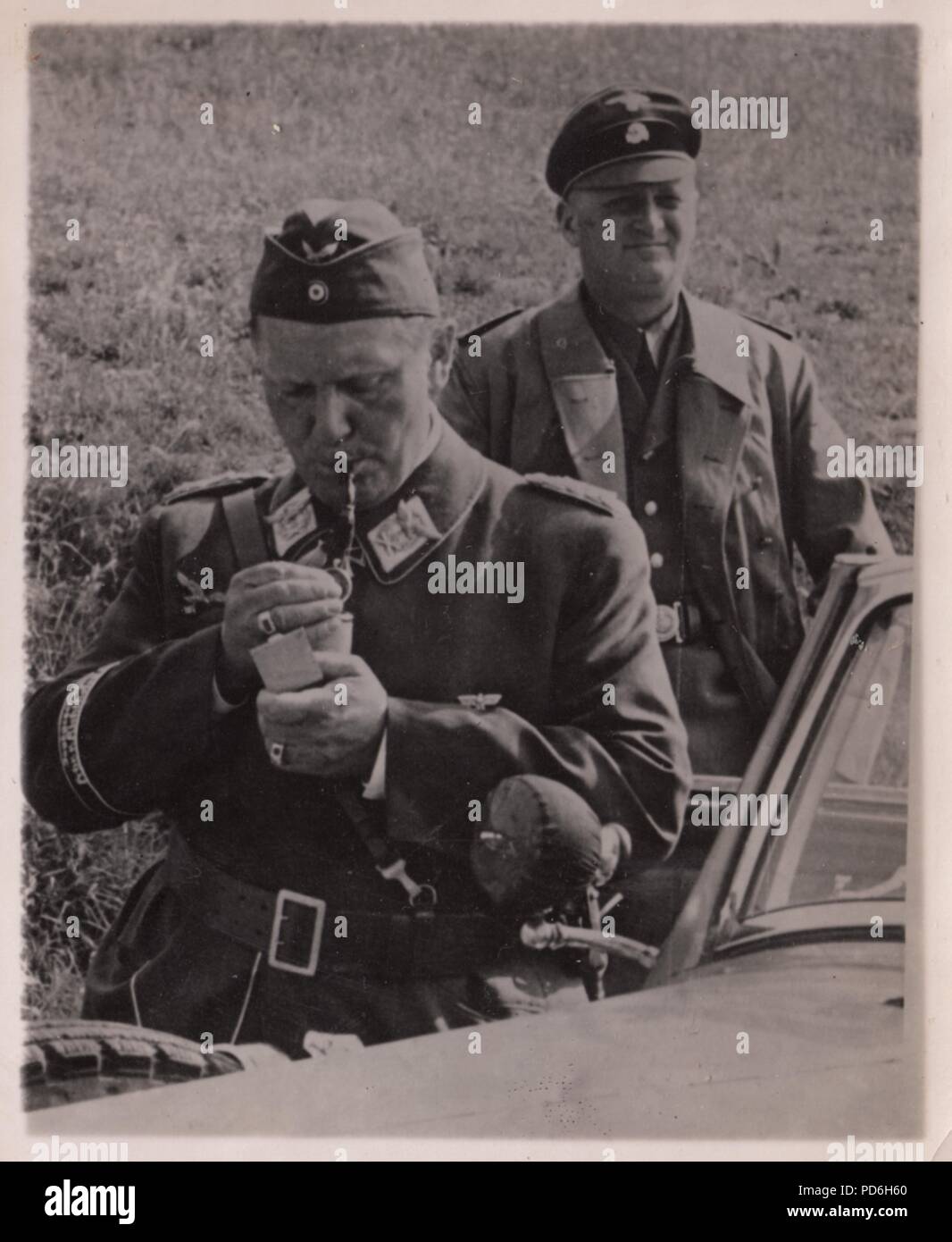 Droit de l'album photo de l'Oberleutnant Oscar Müller de la Kampfgeschwader 1 : Lors d'une visite à II. La Kampfgeschwader 1 Gruppe, le Reichsmarschall Hermann Göring, allume sa pipe, tandis que son chauffeur SS tient la porte de la voiture. L'été 1940 Banque D'Images