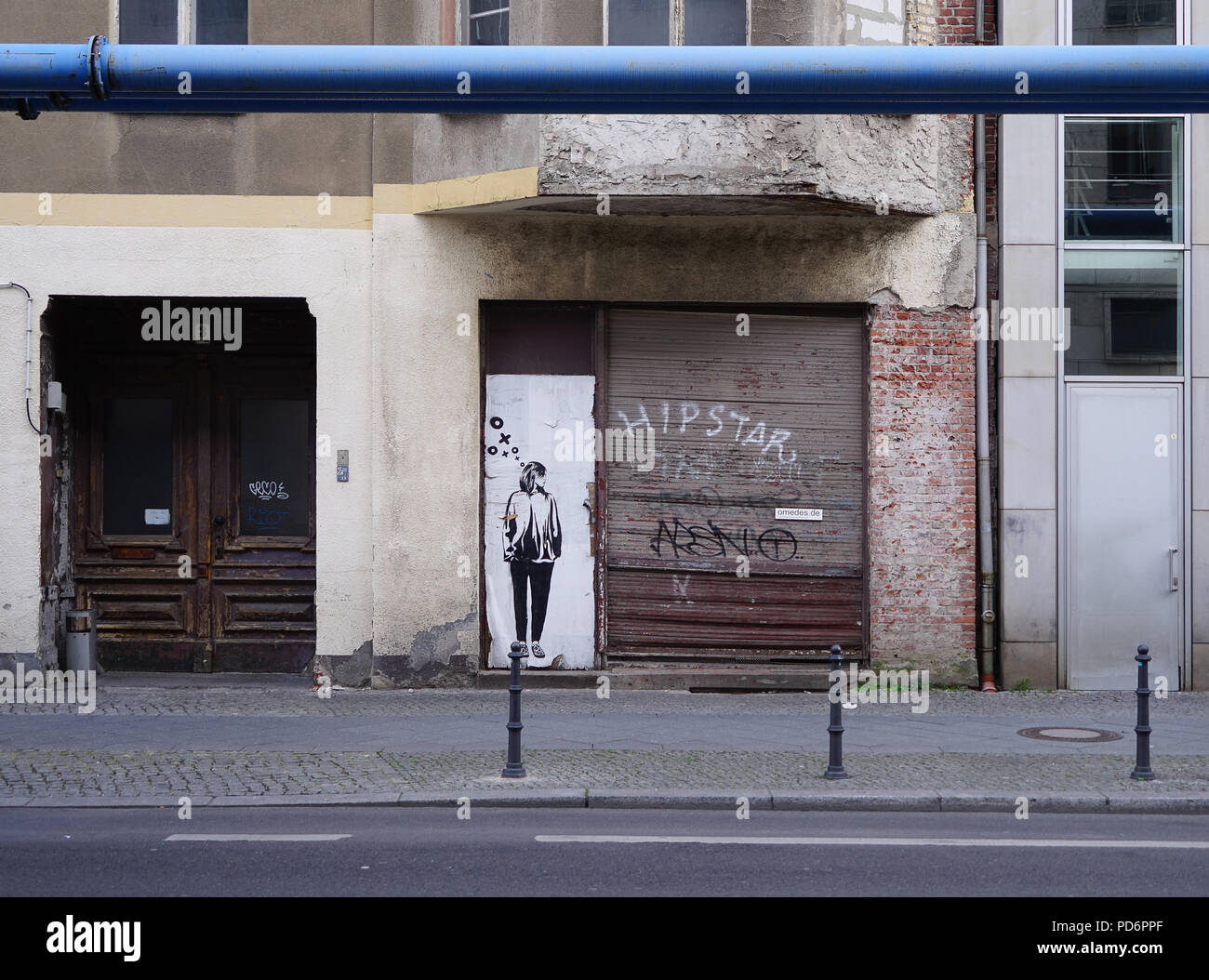 Figure en pochoir d'art urbain à côté d'un volet tagué de graffitis sur une façade de boutique délabrée, Berlin, décadence urbaine Banque D'Images