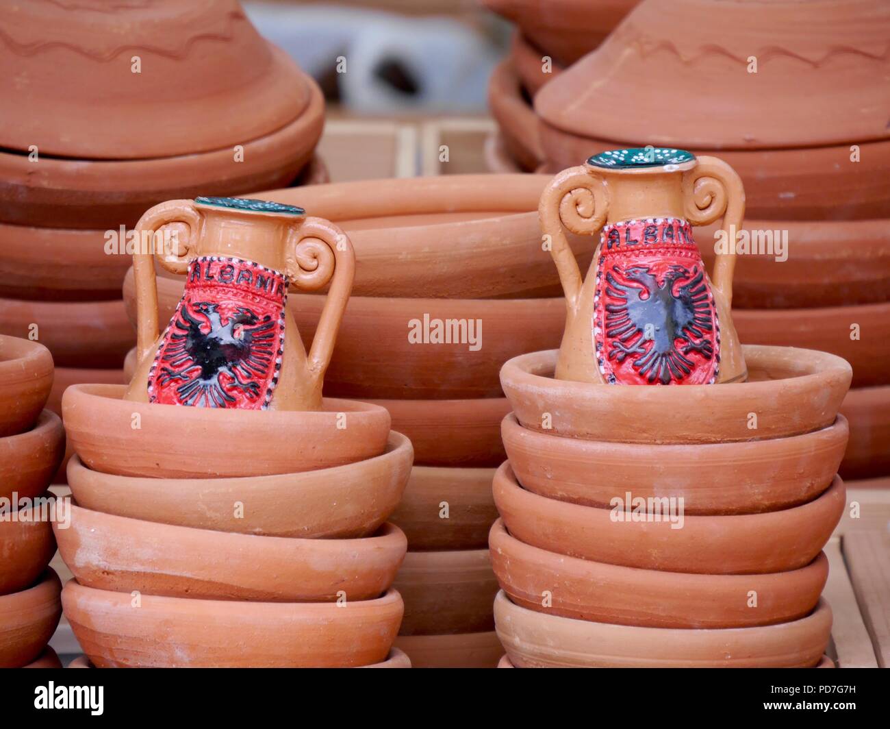 Close up de tas de pots en terre cuite traditionnelle en vente dans le marché Albanais avec 2 pichets décorés de l'aigle à deux têtes du pavillon de l'Albanie Banque D'Images