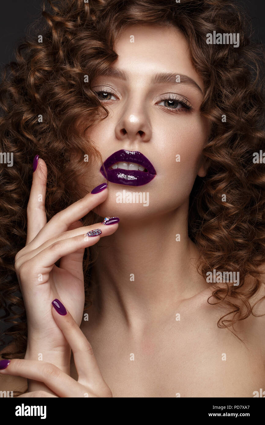 Belle fille avec soir maquillage, lèvres pourpres, boucles et clous. manucure design beauté visage. Banque D'Images