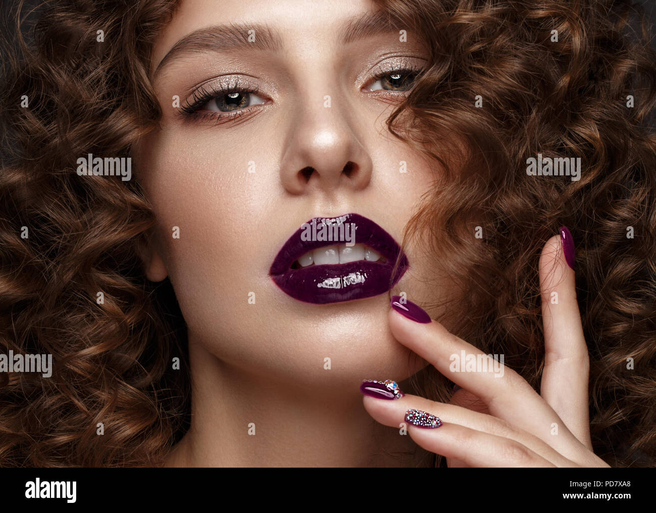 Belle fille avec soir maquillage, lèvres pourpres, boucles et clous. manucure design beauté visage. Banque D'Images