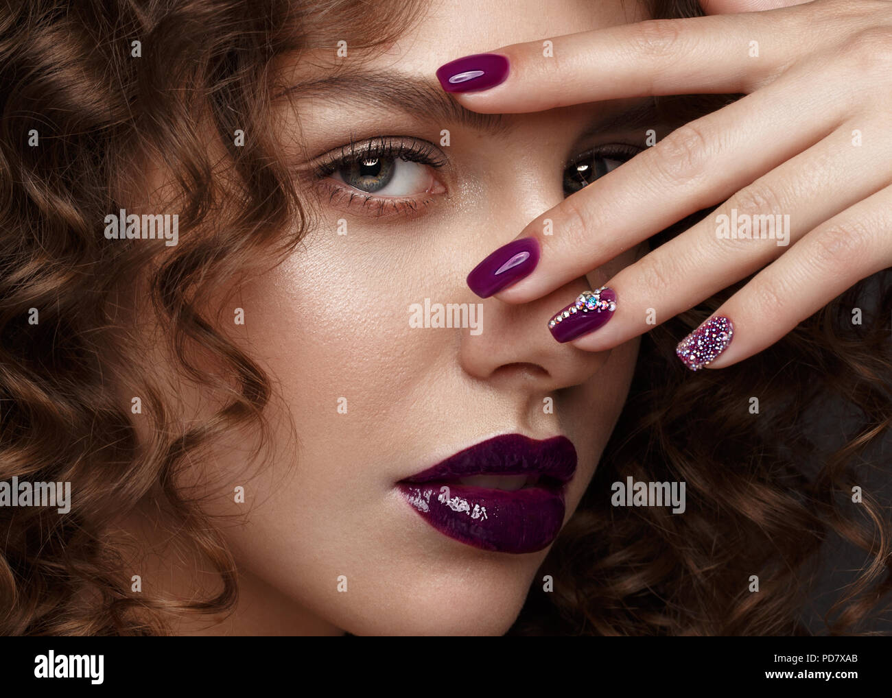 Belle fille avec soir maquillage, lèvres pourpres, boucles et clous. manucure design beauté visage. Banque D'Images