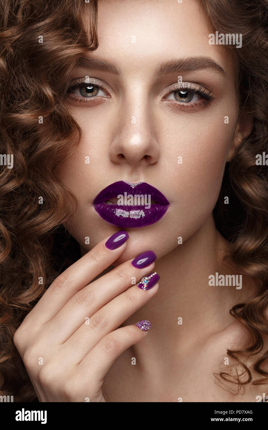 Belle fille avec soir maquillage, lèvres pourpres, boucles et clous. manucure design beauté visage. Banque D'Images