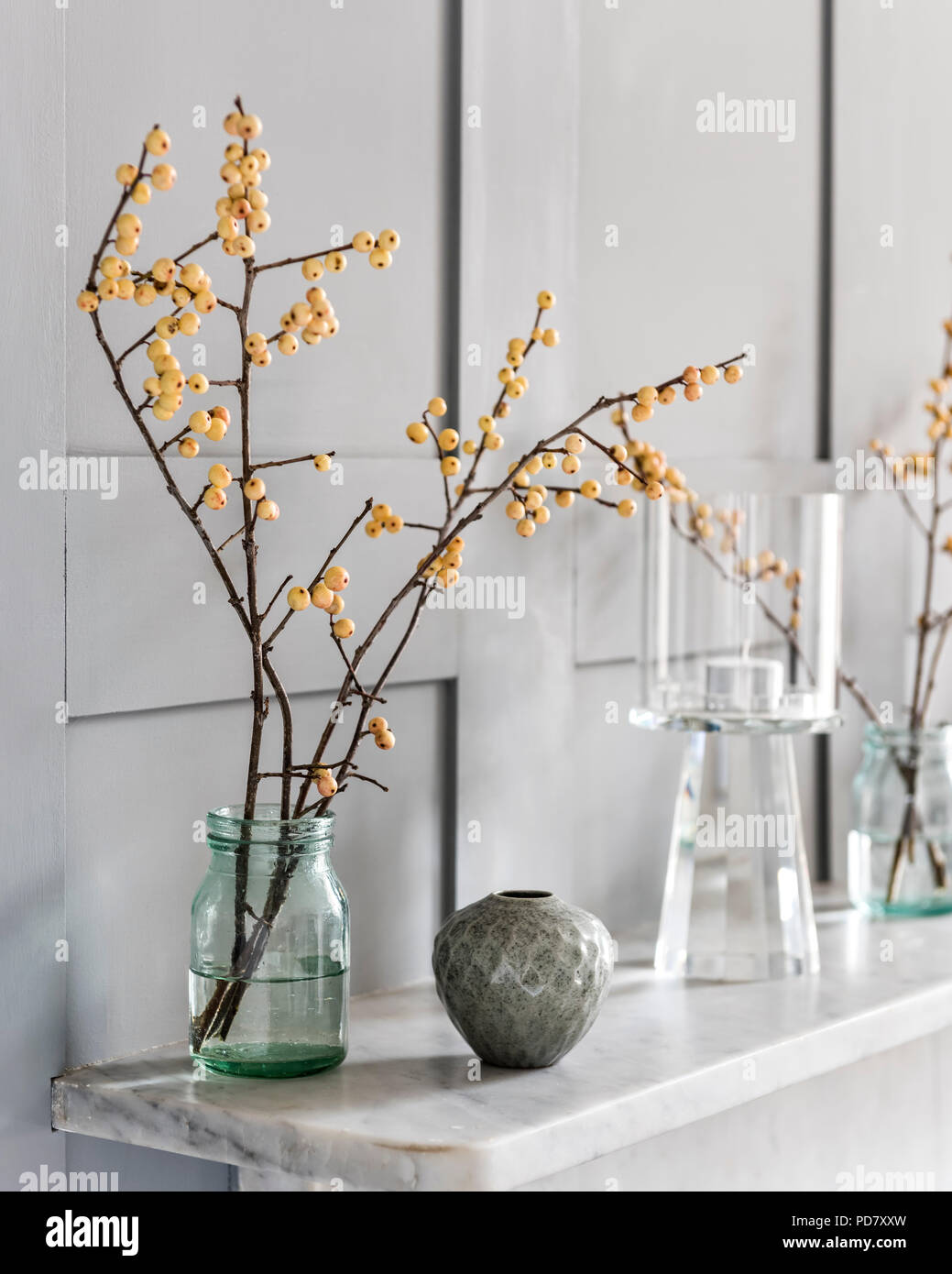 Branches de l'hiver de l'or dans la bouteille de lait en verre et un pot par Akiko Hirai sur la cheminée Banque D'Images