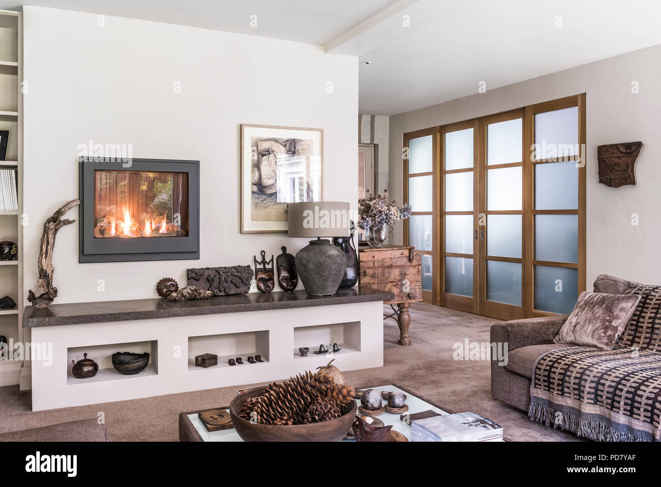 Portes coulissantes opaques dans salon avec tapis indiens par Jacaranda de Kendal tapis de qualité. Un feu de gaz Dru a été placée dans le mur au-dessus de Banque D'Images